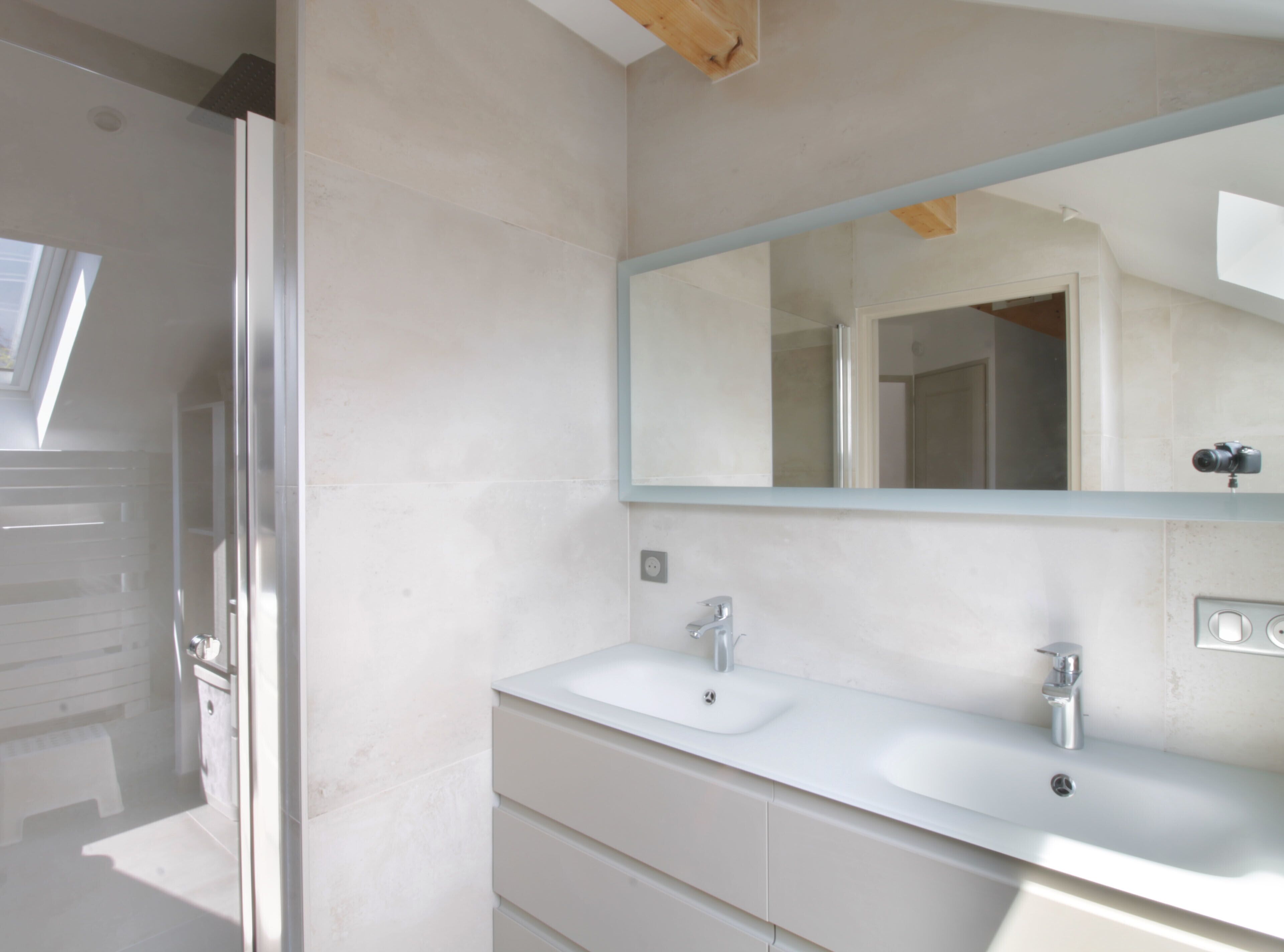 Un baño moderno con un espejo grande, dos lavamanos y una ducha.
