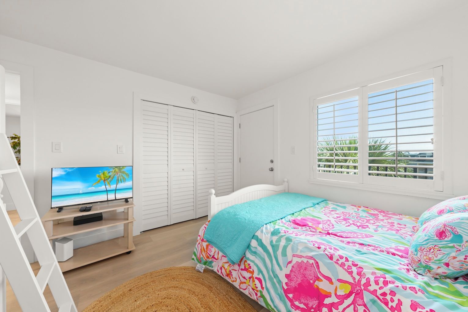 A bedroom with a bed, a TV, a wardrobe, and a window with blinds.