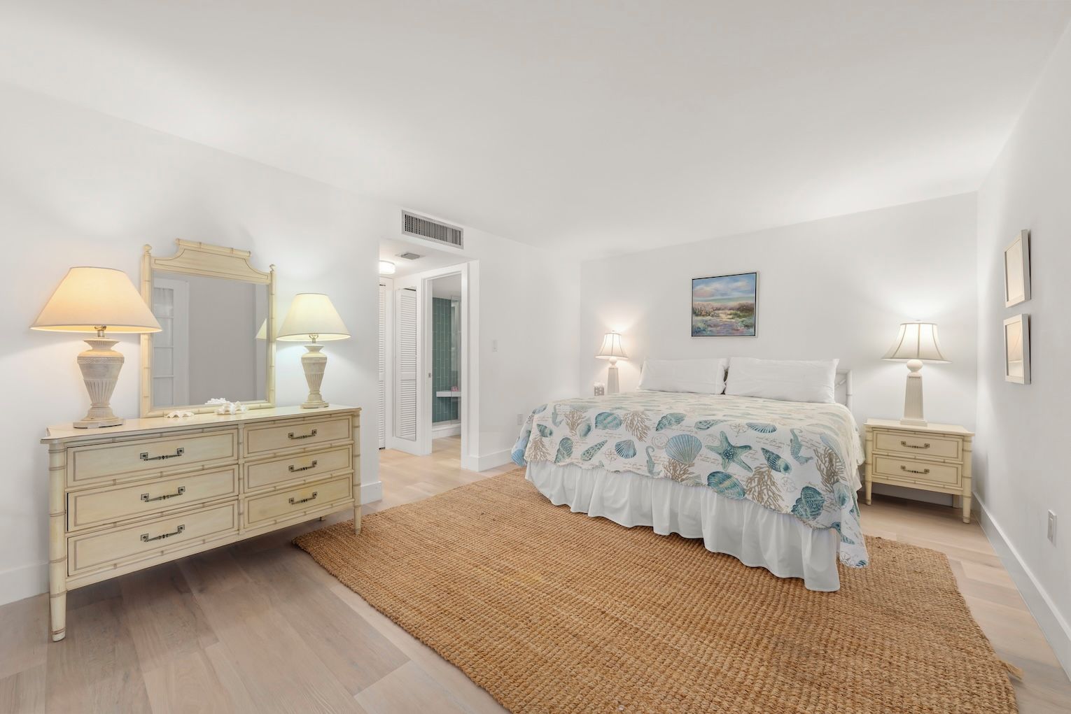 A bedroom with a bed, bedside tables, a dresser, a mirror, and a rug.