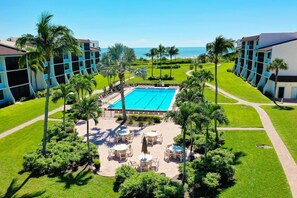 A resort with a central swimming pool, surrounded by palm trees and lounge chairs. - Loggerhead Cay #474 is a stunning 2 brm, 2 bath condo located on Sanibel! (Sanibel)