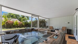 A hot tub with a view of a garden and a patio area with chairs and a table. - Tropical Tiki Hot Tub Pool Tiki Bar Game Room Pool Table 4 miles to Beach (Vero Beach)