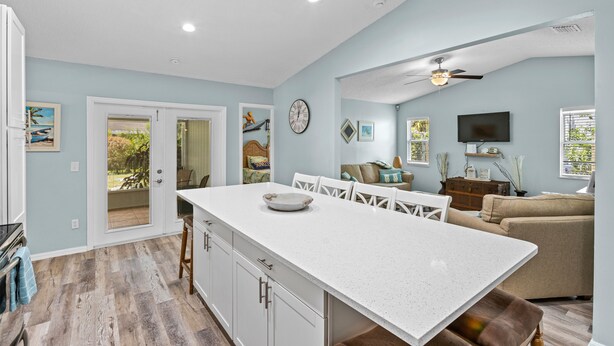 A spacious kitchen with a large island, white cabinetry, and a dining area with a table and chairs. - Tropical Tiki Hot Tub Pool Tiki Bar Game Room Pool Table 4 miles to Beach (Vero Beach)