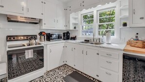 Una cocina moderna con armarios blancos, horno integrado, microondas y una ventana con vistas a zonas verdes.