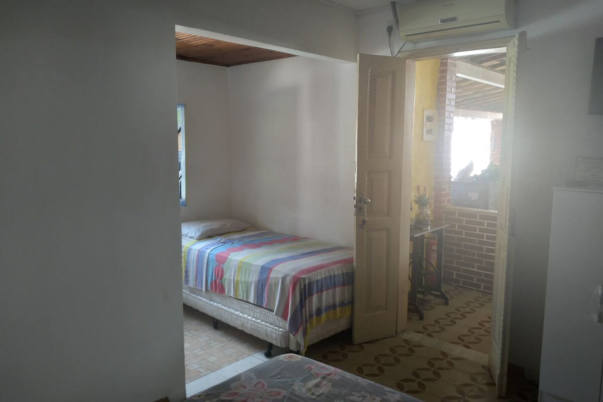 Ein kleines Schlafzimmer mit einem Bett, einer Tür zu einem anderen Raum und einem Fliesenboden.