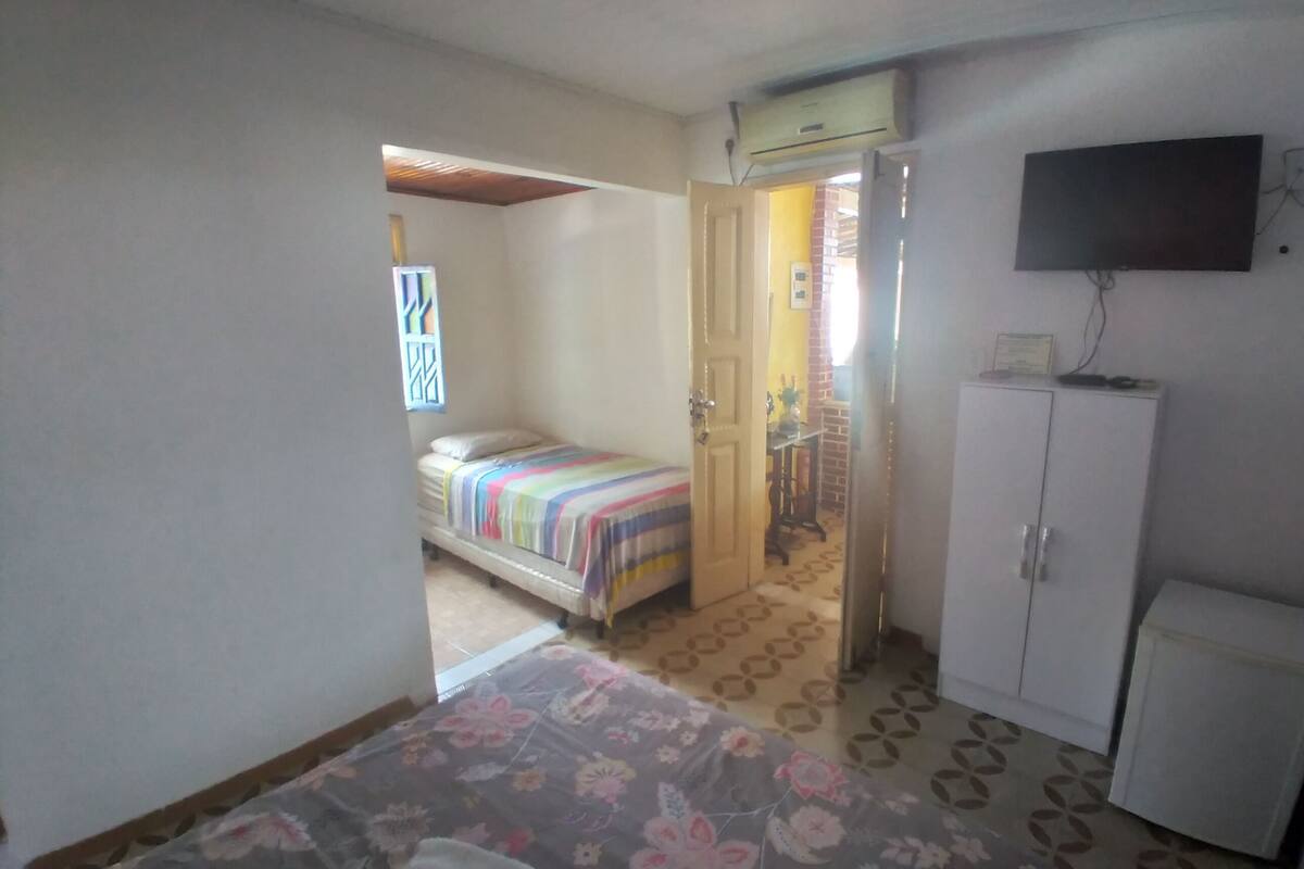Ein Schlafzimmer mit Bett, Kleiderschrank und Fernseher an der Wand.