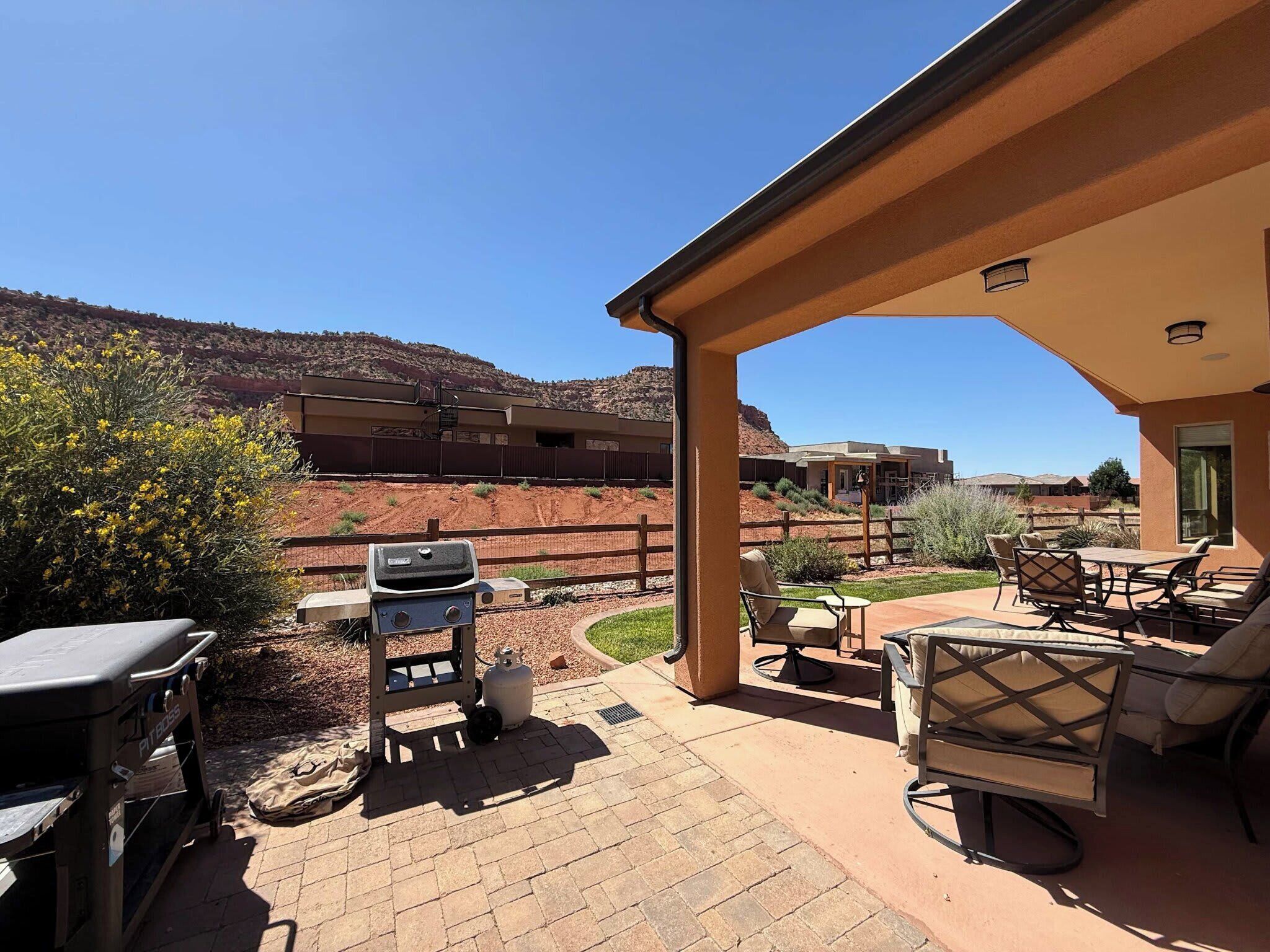 Covered patio with BBQ grill, outdoor dining, and peaceful red rock views—perfect for sunset dinners.
