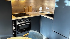 Une cuisine moderne avec un plafond en bois, un four encastré, un évier et un coin repas comprenant une table et des chaises.
