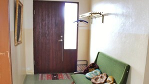 A room with a wooden door, a green sofa with cushions, a small table, and a wall-mounted drying rack. - Old Authentic Icelandic Farmhouse (Laugar)