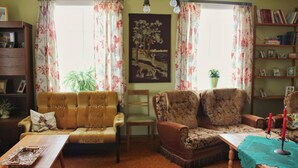 A cozy living room with a sofa, armchair, and a table with a placemat. - Old Authentic Icelandic Farmhouse (Laugar)
