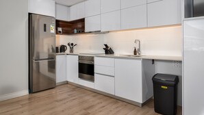 Une cuisine moderne avec des armoires blanches, des appareils en acier inoxydable et un plan de travail en bois.