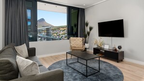 Un salon moderne avec une grande fenêtre, un canapé, une table basse et un téléviseur à écran plat.