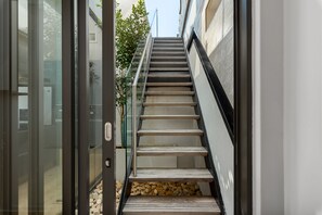 Eine moderne Treppe mit Glasgeländern und einem Steinfuß, die zu einer oberen Ebene führt.