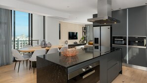 Una cocina moderna con una isla central, un comedor con mesa y sillas, y un ventanal que ofrece vistas a la ciudad.