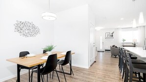 A modern kitchen with a wooden dining table, black chairs, and pendant lighting. - Paisley. Sleeps 6. Dog Friendly. A/C (Southwest)
