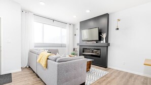 A modern living room with a grey sofa, a flat-screen TV, and a fireplace. - Paisley. Sleeps 6. Dog Friendly. A/C (Southwest)