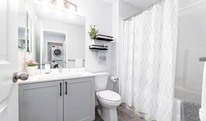 Un bagno moderno con il water, un lavandino e una lavatrice a incasso.