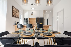 Enjoy meals in this stylish dining area with a rectangular table for four, pendant lights, and a large framed artwork.
