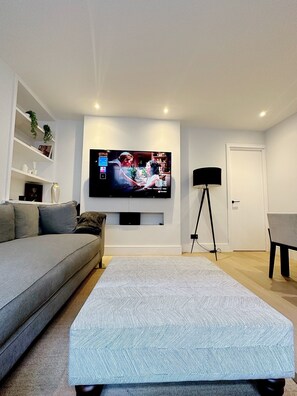 Relax in this stylish living room with a flat-screen TV, comfortable sofa, and cozy ottoman.