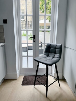 Experience the perfect blend of indoor-outdoor living in this stylish space, featuring a comfortable chair and double doors leading to a serene outdoor area.