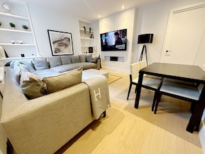 Relax in this stylish living room with a large L-shaped sofa, flat-screen TV, and dining area.