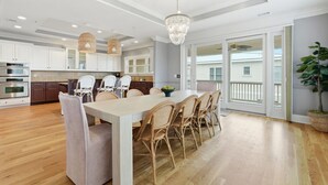 A spacious kitchen with white cabinets, a dining area with wicker chairs, and a large chandelier. - 4 Bed 5 Bath Luxury Beach Front Home w/Ocean Views (Tybee Island)