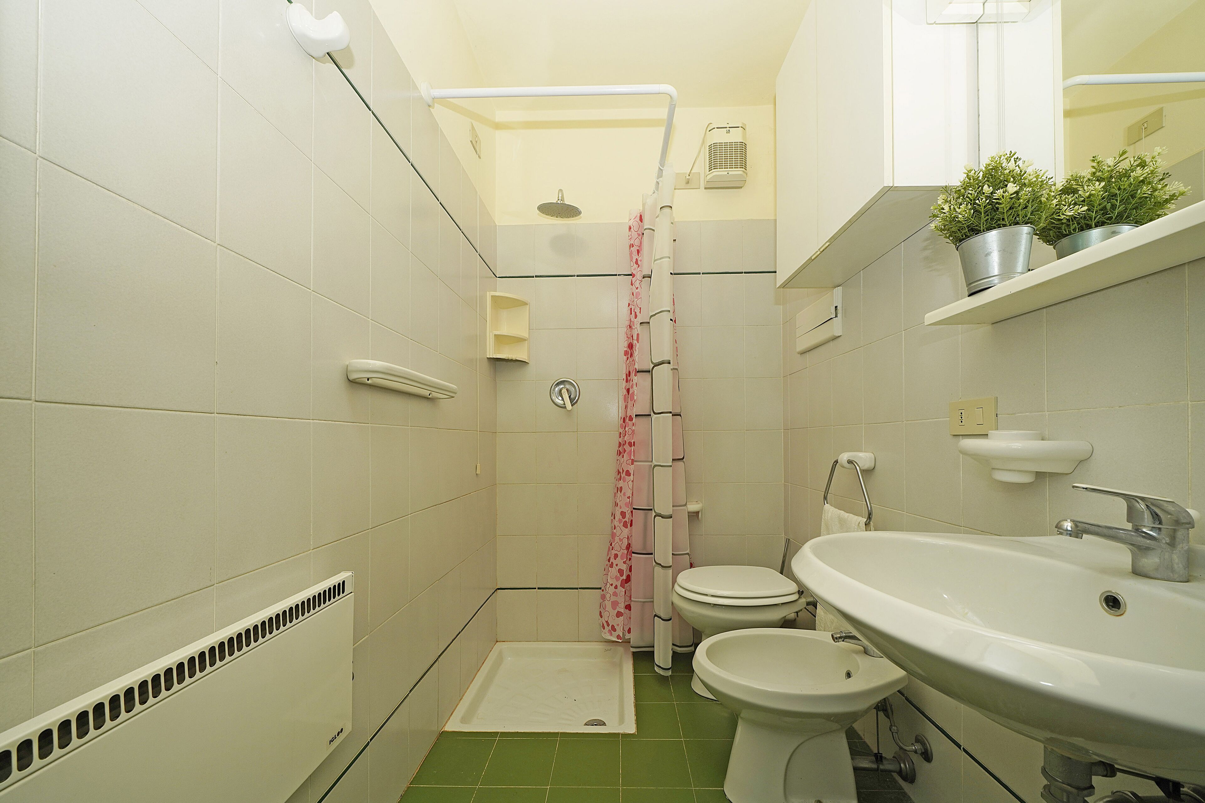 A small bathroom with a shower, toilet, bidet, and sink.