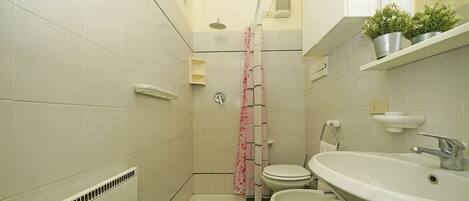 A small bathroom with a shower, toilet, bidet, and sink.