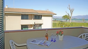 Un balcon avec une table, une bouteille et des verres, donnant sur un quartier résidentiel et un plan d’eau.