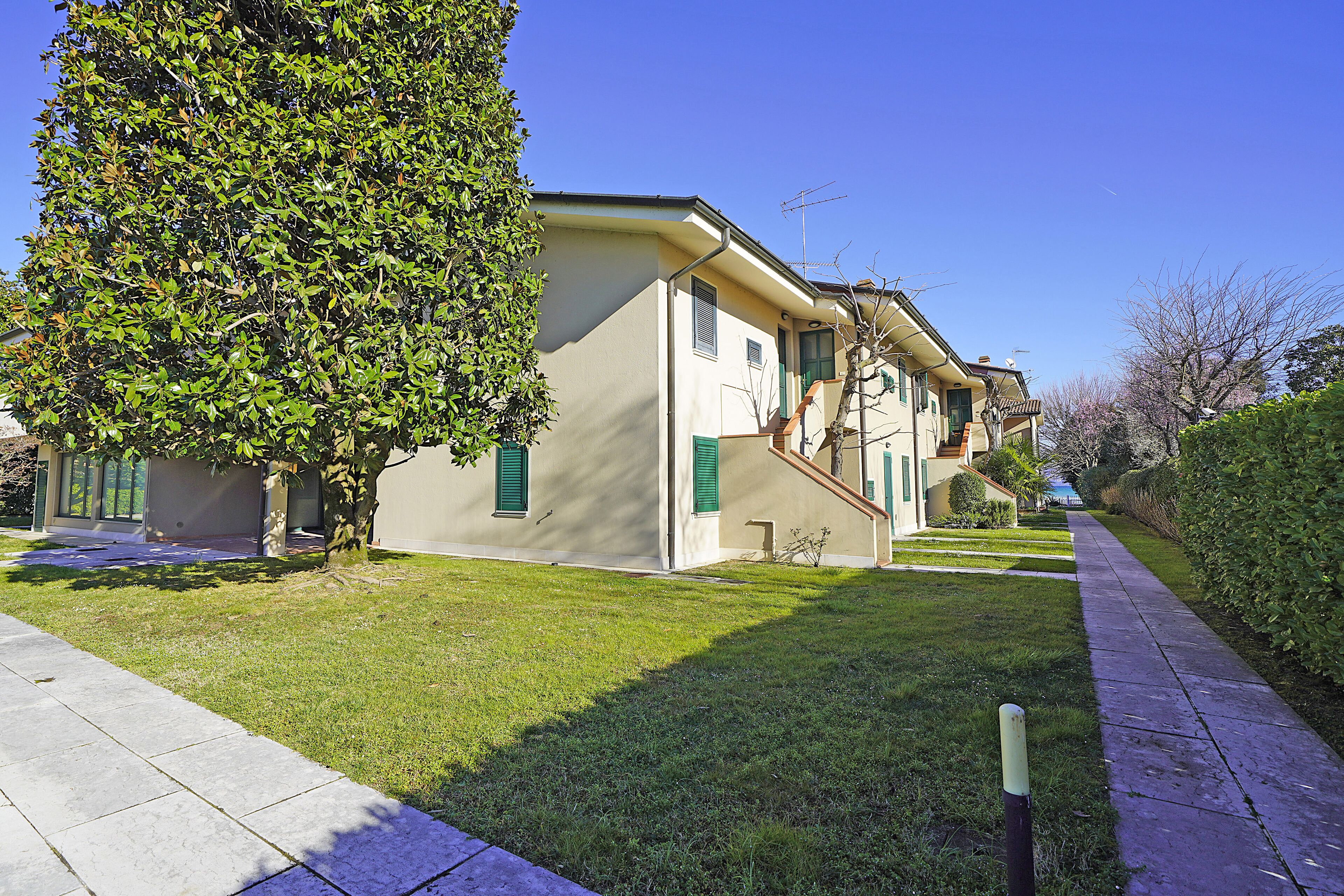 A residential building with a well-maintained lawn, a sidewalk, and a clear blue sky.