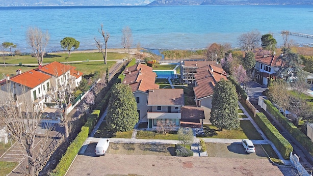 Un quartier résidentiel avec des maisons, un parking et un lac, avec des montagnes en arrière-plan.