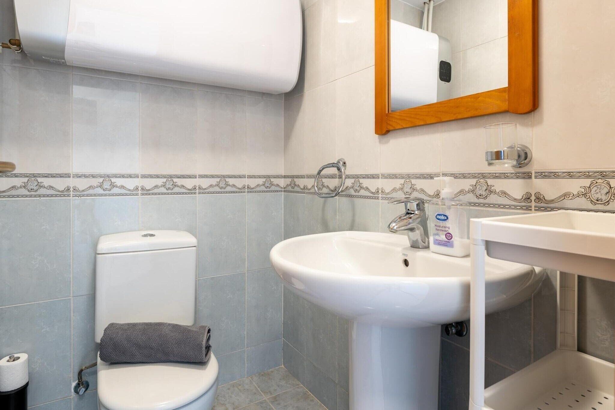 A bathroom with a toilet, sink, and mirror.