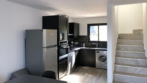 Eine kompakte Küche mit Kühlschrank, Backofen, Mikrowelle und Waschmaschine.