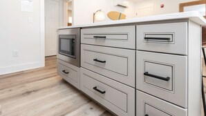 Een kitchenette met een ingebouwde magnetron, meerdere lades en een aanrecht.