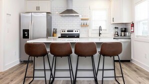 A modern kitchen with a central island, stainless steel appliances, and bar stools. - Teahupo'o - Loft #2 - 8 min walk to the beach (Virginia Beach)