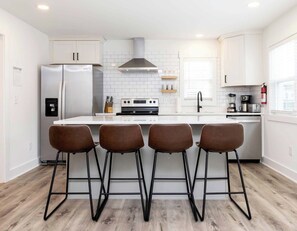A modern kitchen with a central island, stainless steel appliances, and bar stools.
