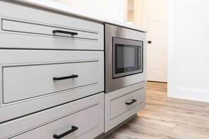 A kitchen with a built-in microwave, stainless steel cabinets, and a wooden floor.