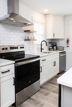 Una cucina moderna con mobili bianchi, elettrodomestici in acciaio inossidabile e forno integrato.
