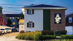 A building with a sign for Atlantic Park Lofts, featuring a white brick facade, a wooden panel section, and a green vertical garden. - Jeffreys Bay - Loft #3 - 8 min walk to beach (Virginia Beach)