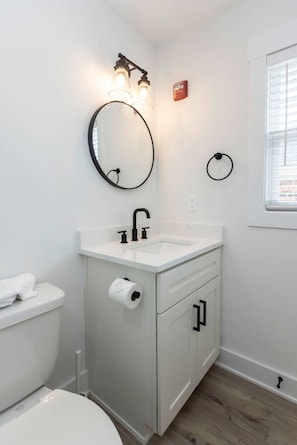 A bathroom with a toilet, sink, mirror, and towel rack.