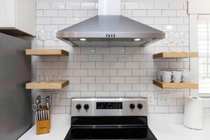 A modern kitchen with a stainless steel range hood, wooden shelves, and a built-in oven. - Malibu - Loft #4 - 8 min walk to the beach (Virginia Beach)
