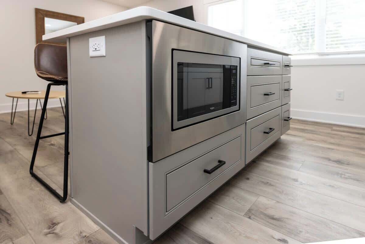 Une petite cuisine équipée comprenant un four à micro-ondes, un petit réfrigérateur et un meuble à tiroirs.
