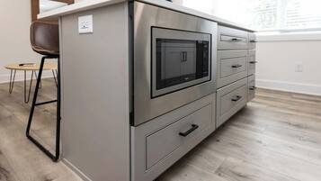 Une petite cuisine équipée comprenant un four à micro-ondes, un petit réfrigérateur et un meuble à tiroirs.