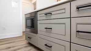 Una cocina con microondas, varios cajones y piso de madera.