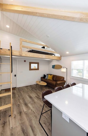 Ein Loft-Zimmer mit Stockbett, Essbereich und Sitzecke inklusive Sofa und Sesseln.