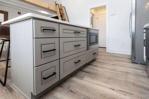 A kitchen with a built-in oven, a refrigerator, and a wooden floor.