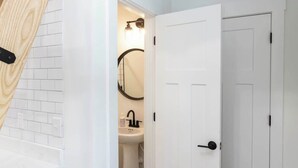 A modern bathroom with a white sink, a mirror, and a white door. - Pipeline - Loft #9 - 8 min walk to the beach (Virginia Beach)