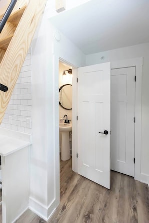 Un baño moderno con un lavamanos blanco, un espejo y una puerta blanca.