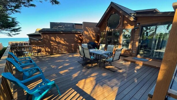 Une terrasse en bois avec une table et des chaises, donnant sur une étendue d’eau.