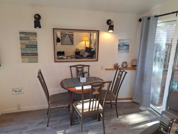 Un comedor con una mesa y sillas de madera, un espejo, decoración en la pared y un ventanal con cortinas.