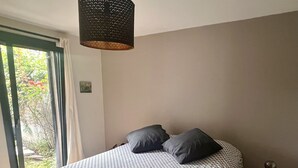 A bedroom with a bed, a small round table, and a hanging light fixture. - Charmante Maison Familiale (Gradignan)